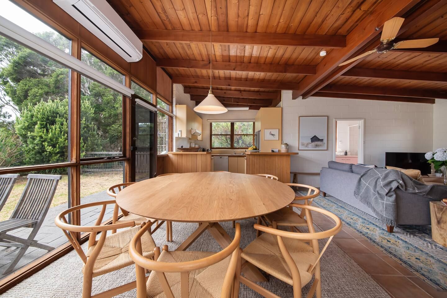 The dining table by the deck, with gum trees outside the windows